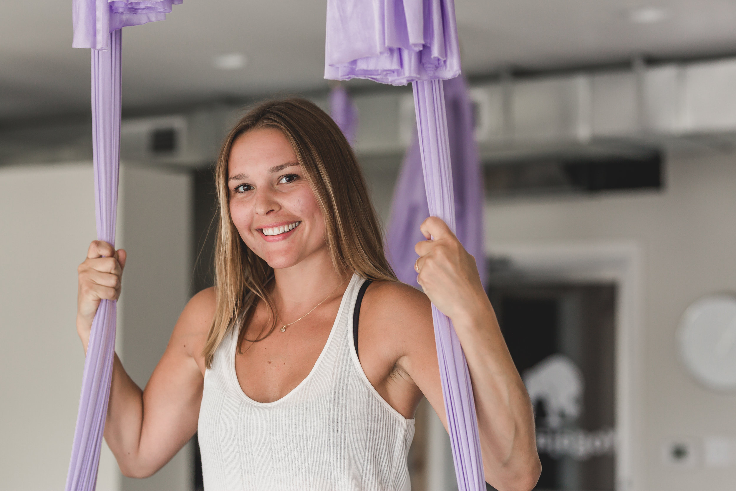 Belle standing in natural light with aerial yoga silks